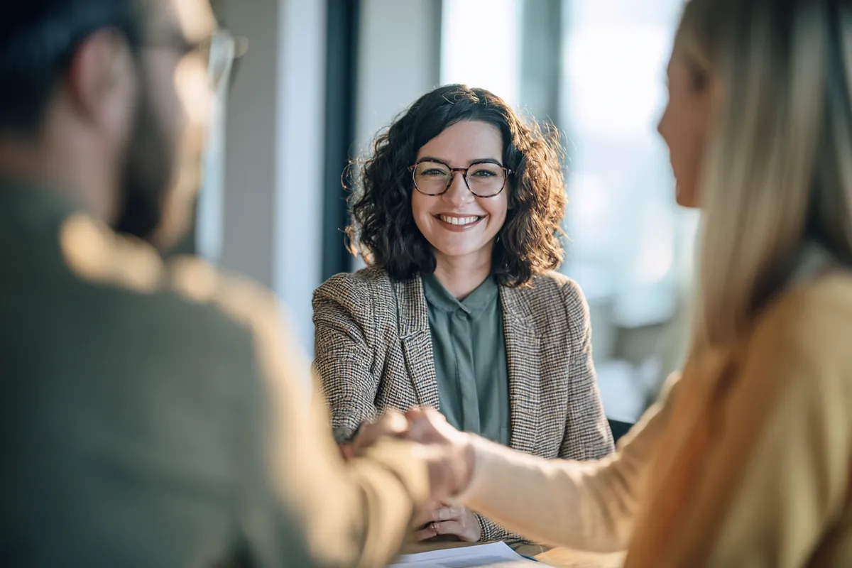 Couple shaking hands with a loan advisor after finalizing an agreement in a bright office
